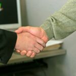 Professional handshake in an office setting, possibly signifying agreement on funding for hydrogen projects.