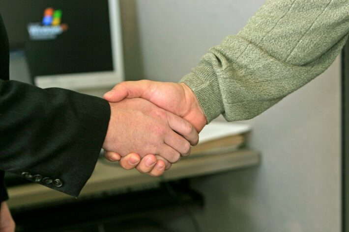 Professional handshake in an office setting, possibly signifying agreement on funding for hydrogen projects.