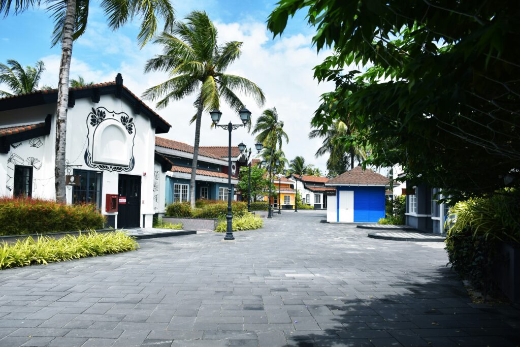 A serene, resort-style street with unique buildings and palm trees, illustrating potential high-value properties that show the benefits of off-market real estate deals for investors.