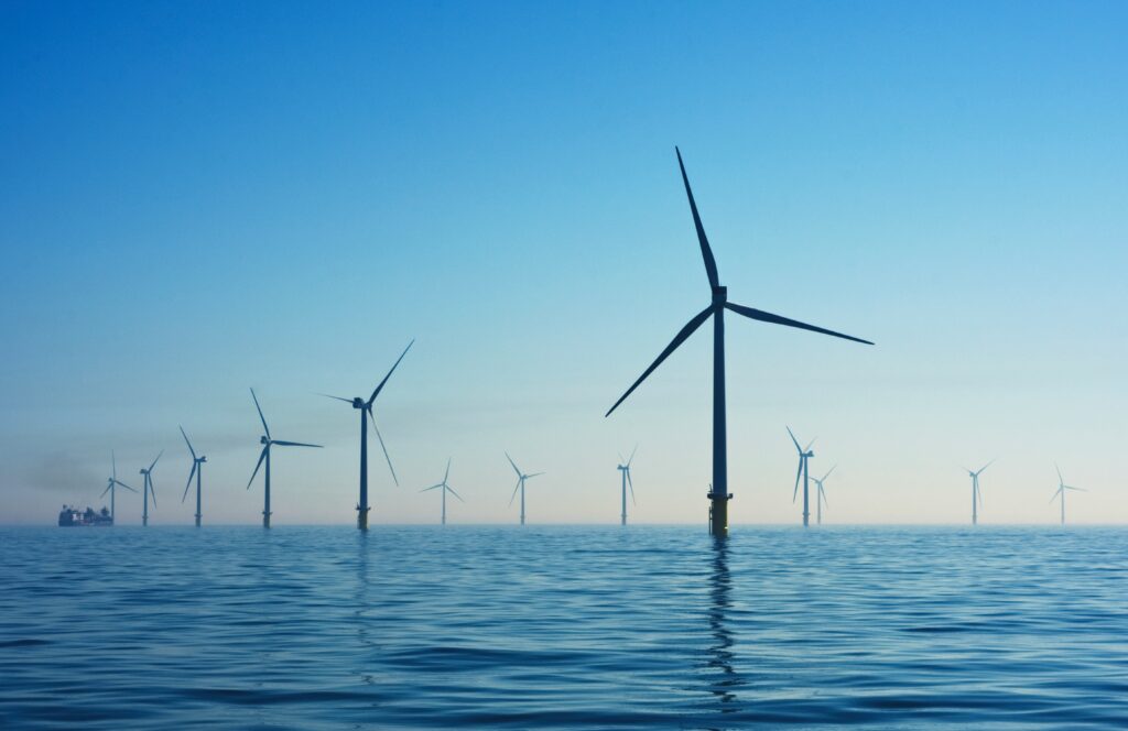 Offshore wind farm with multiple wind turbines on a calm blue sea, representing renewable energy consulting expertise.